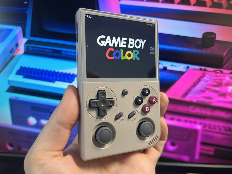 Der BATLEXP G350 zeigt den Startbildschirm des Game Boy Color Logos vor leuchtenden Retro‑Computern. Das Display ist klar und gleichmäßig ausgeleuchtet, Bedienelemente gut erkennbar.